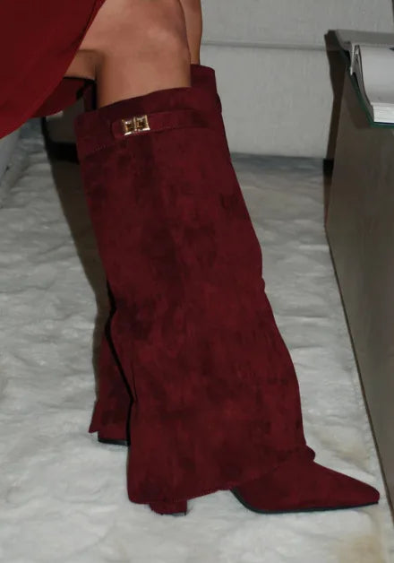 Maroon knee-high boots with a gold buckle on a white surface.